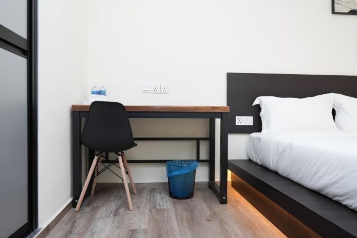 A compact hotel room with a bed, a desk, and a chair.