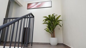 A staircase with a metal railing and a potted plant on the landing. - Anta Hotel  (Johor Bahru)