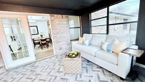 A modern living room with a white sofa, a coffee table, and a herringbone-patterned floor.