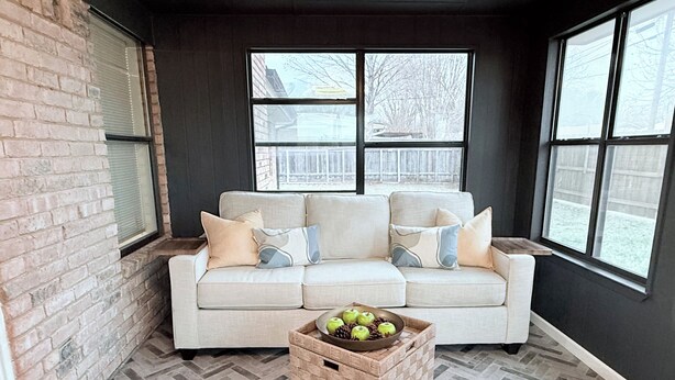 A cozy corner with a beige sofa, a herringbone-patterned floor, and a basket of apples.