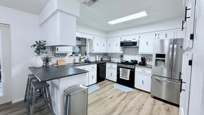 A modern kitchen with white cabinets, stainless steel appliances, and a central island with stools.