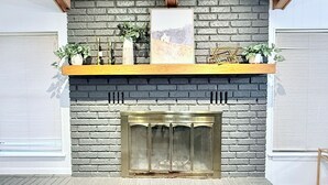 A fireplace with a brick surround, a wooden mantel, and a framed picture above it.