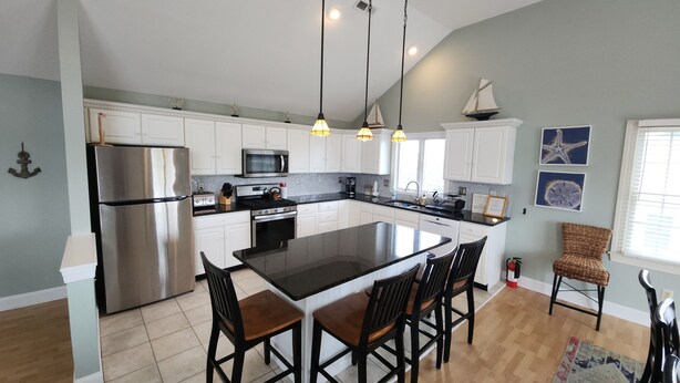 A modern kitchen with white cabinets, stainless steel appliances, and a central island with four chairs. - Henry's Hideaway-Cape May- 2.5 blocks to beach- 5 BR- Elevator (Cape May)