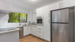 Eine moderne Küche mit weißen Schränken, Edelstahlgeräten und einem Fenster mit Blick auf Grünflächen.