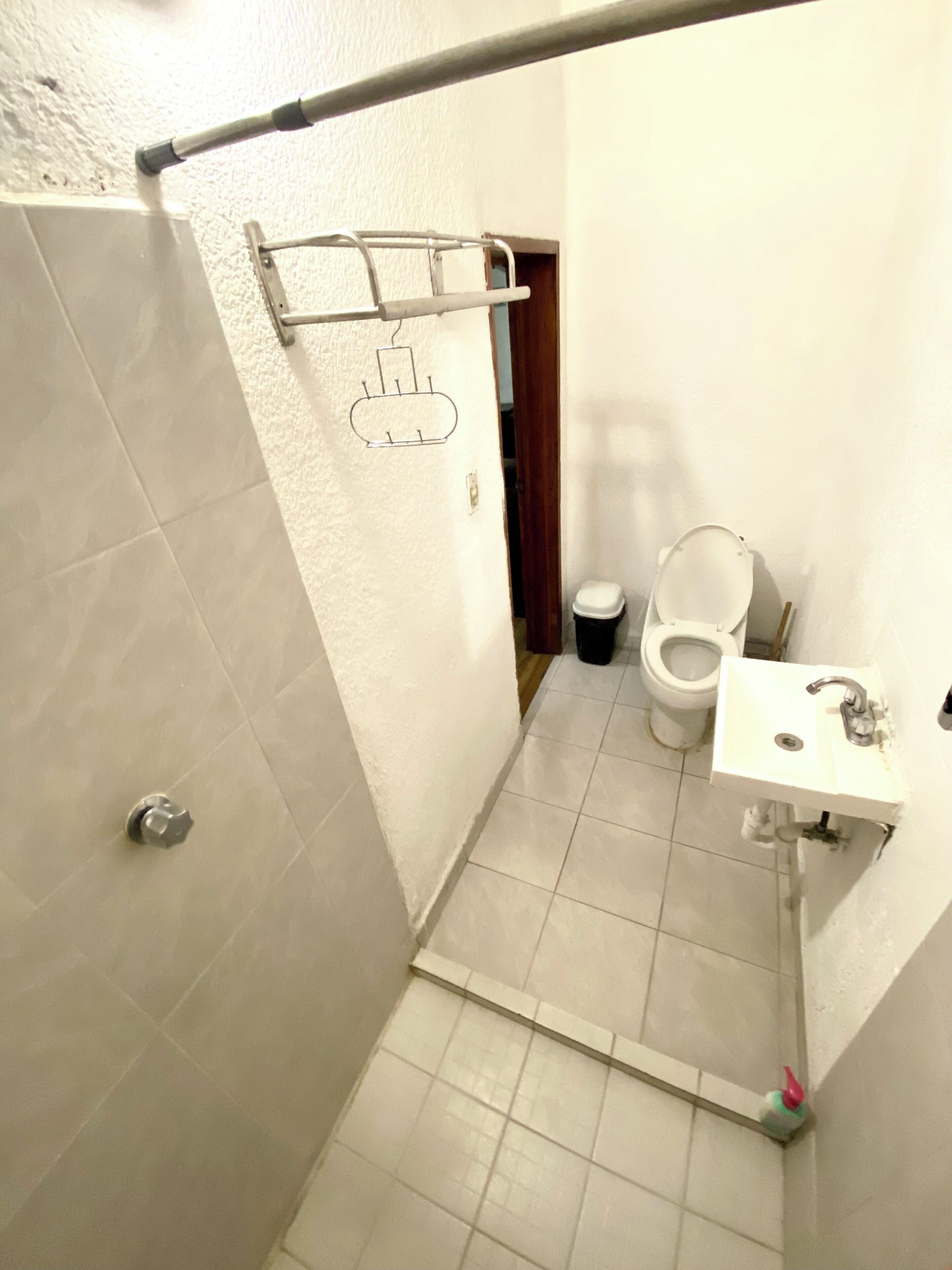 A small bathroom with a toilet, sink, and shower area.