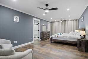 A bedroom with a bed, a nightstand, a dresser, a ceiling fan, and a door leading to another room. - Cool New Dover Home (Dover)