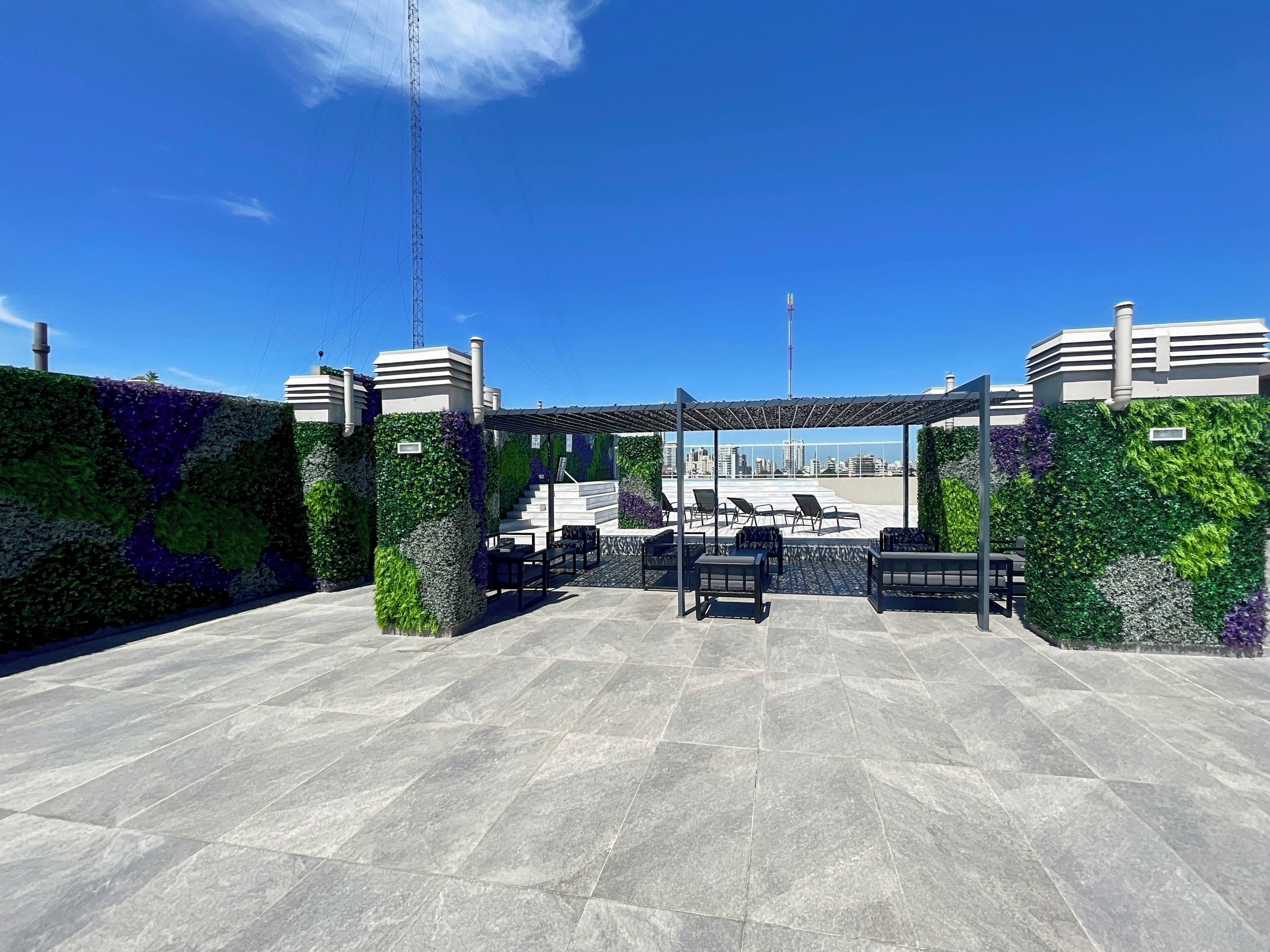 A rooftop terrace with a pergola, seating area, and city skyline views.
