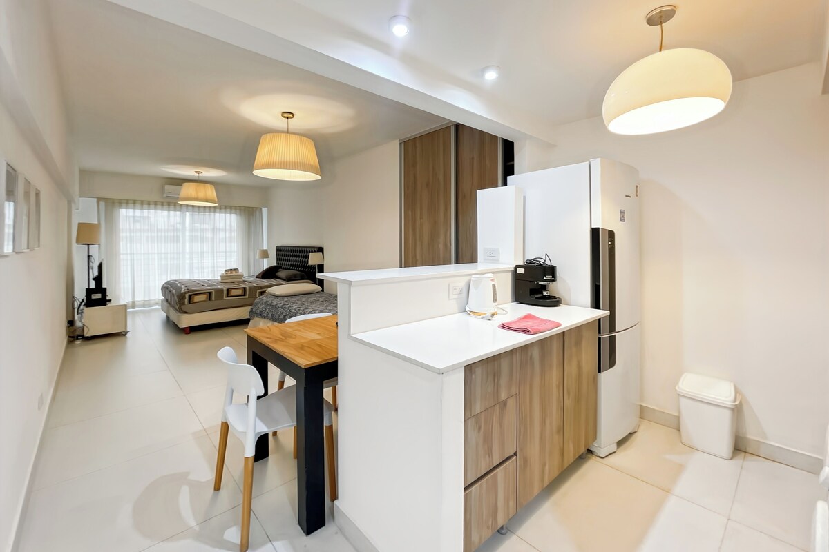 A modern kitchen with a white countertop, wooden cabinets, and a built-in refrigerator.