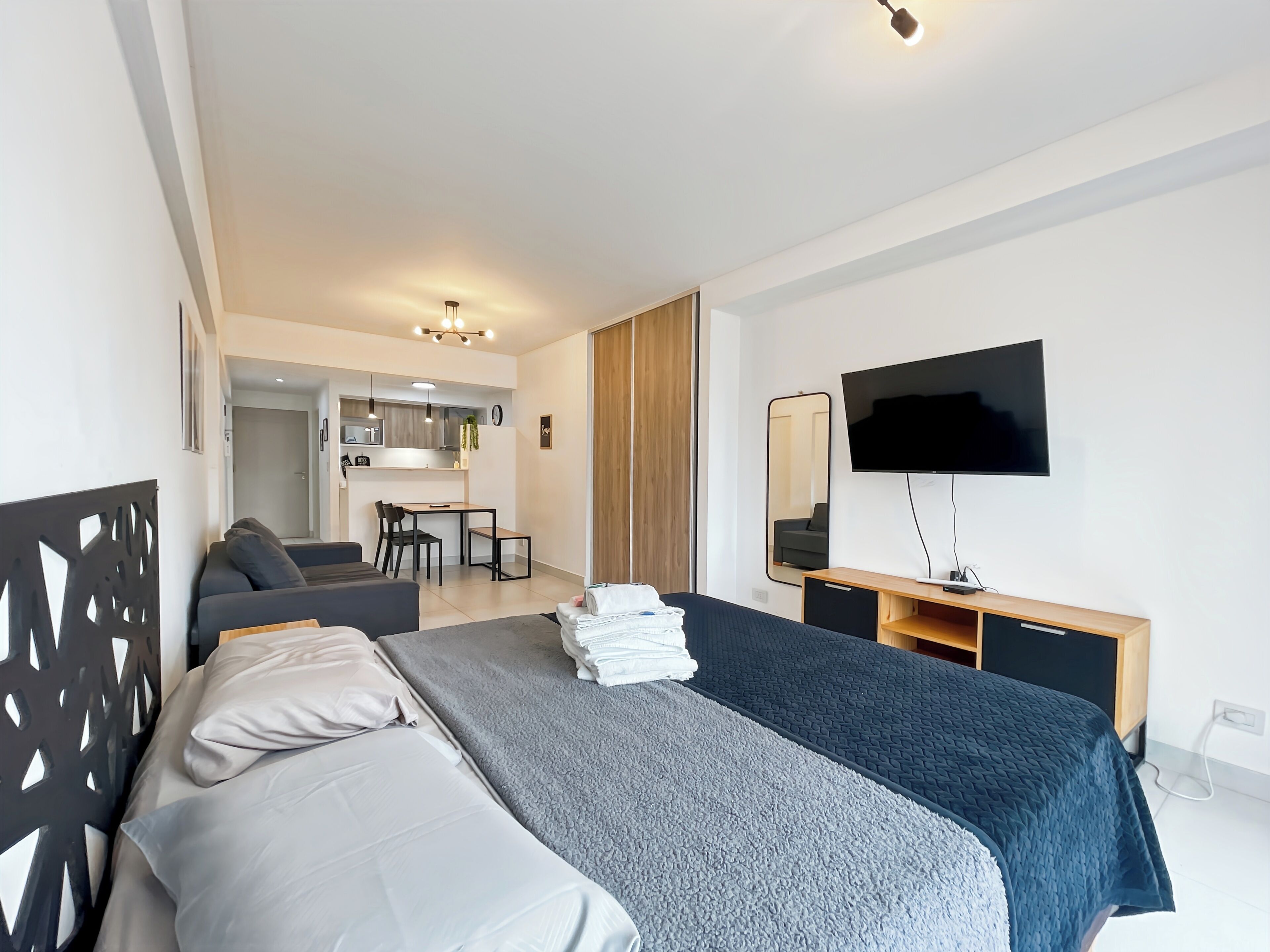 Une chambre d’hôtel moderne équipée d’un lit, d’un bureau, d’une télévision et d’une kitchenette.