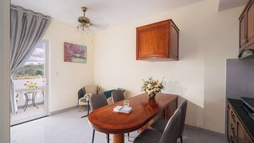 A dining area with a wooden table, chairs, a vase of flowers, and a painting on the wall.