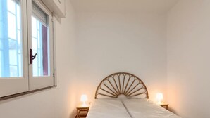 A small, single-bed room with a wooden headboard, two bedside lamps, and a window with a closed door. - Villa Iris with large veranda (San Pietro In Bevagna)