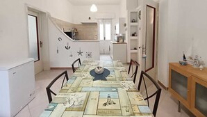 A modern kitchen with white cabinets, a central island, and a dining area with a nautical-themed tablecloth. - Villa Iris with large veranda (San Pietro In Bevagna)