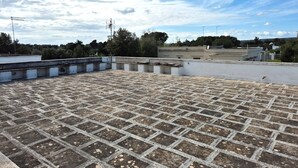 A rooftop terrace with a tiled floor, surrounded by buildings and trees under a partly cloudy sky. - Villa Iris with large veranda (San Pietro In Bevagna)