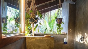 Ein Badezimmer mit einem Holzbac, einem Spiegel und hängenden Pflanzen.