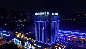 A hotel with a prominent vertical light strip design, multiple parking levels, and a well-lit facade. - Maxshure Mezihoo Hotel (Shanghai)