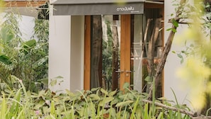 A modern building with a minimalist design, featuring a glass entrance and a wooden door. - Baan phandao (Rim Nuea)