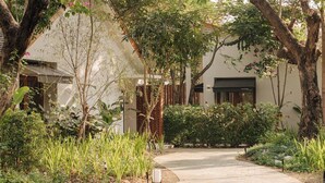 A pathway leading to a building with a brick facade and a covered entrance. - Baan phandao (Rim Nuea)