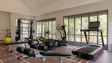 A gym with various exercise equipment, large windows, and a clear view of the outdoors.