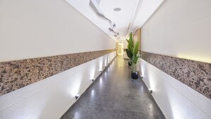 A modern hallway with a polished granite floor, white walls, and a ceiling with recessed lighting.