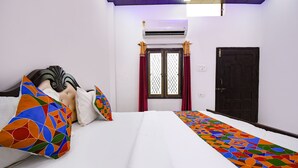 Ein Hotelzimmer mit einem Bett, einem Vorhangfenster, einer Klimaanlage und einer Tür.
