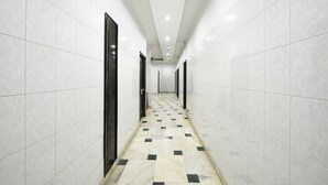 A corridor with white tiled walls and a checkered floor. - Fabhotel Delhi Darbar (New Delhi)