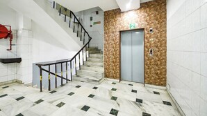 A staircase with a marble floor leading to an elevator. - Fabhotel Delhi Darbar (New Delhi)