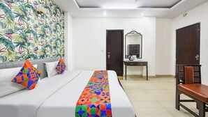 A hotel room with a bed, a desk, a chair, a ceiling fan, and a door. - Fabhotel Delhi Darbar (New Delhi)
