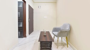 Un couloir étroit avec une table en bois et une chaise grise.