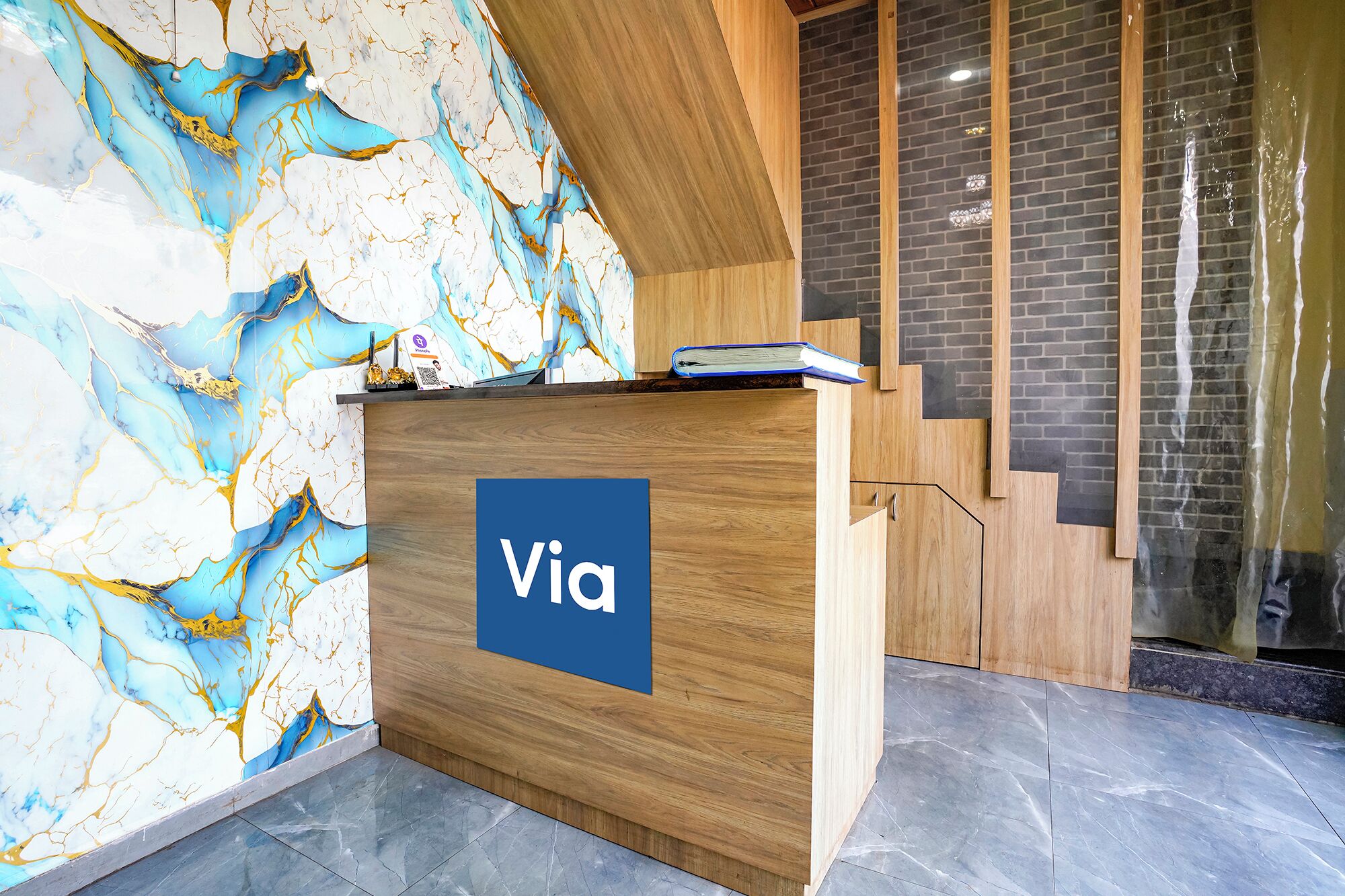 A reception desk with a marble wall and a staircase.