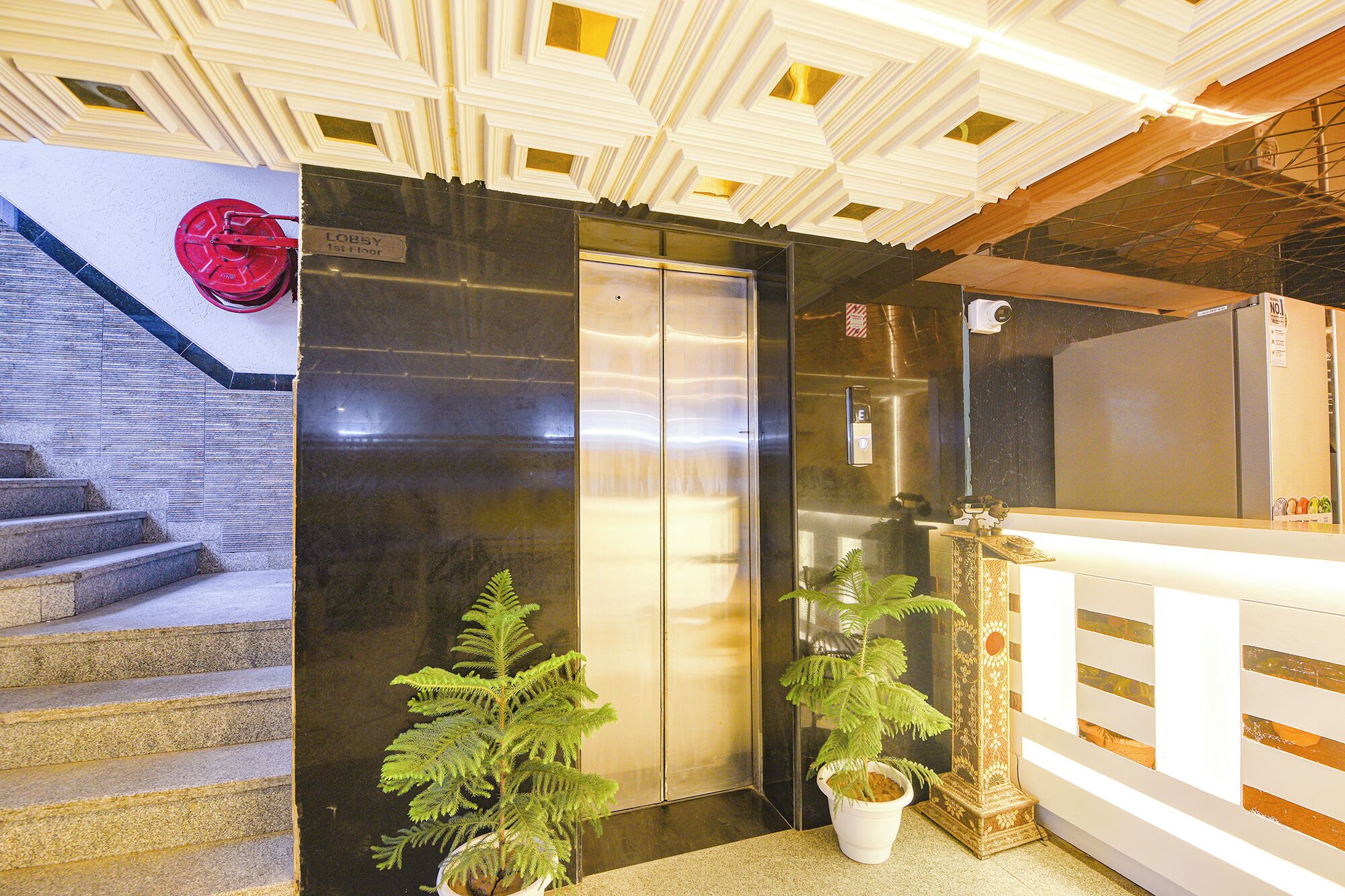 A hotel lobby with a reception desk, a staircase, and an elevator.