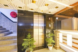 A hotel lobby with a reception desk, a staircase, and an elevator. - FabHotel Dev Palace Naraina (New Delhi)