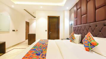 A hotel room with a bed, a headboard, a door, and a hallway.