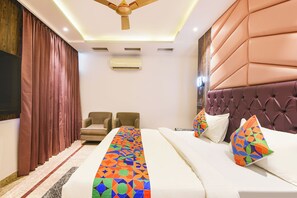 A hotel room with a bed, two armchairs, a ceiling fan, and a wall-mounted air conditioner. - FabHotel Dev Palace Naraina (New Delhi)