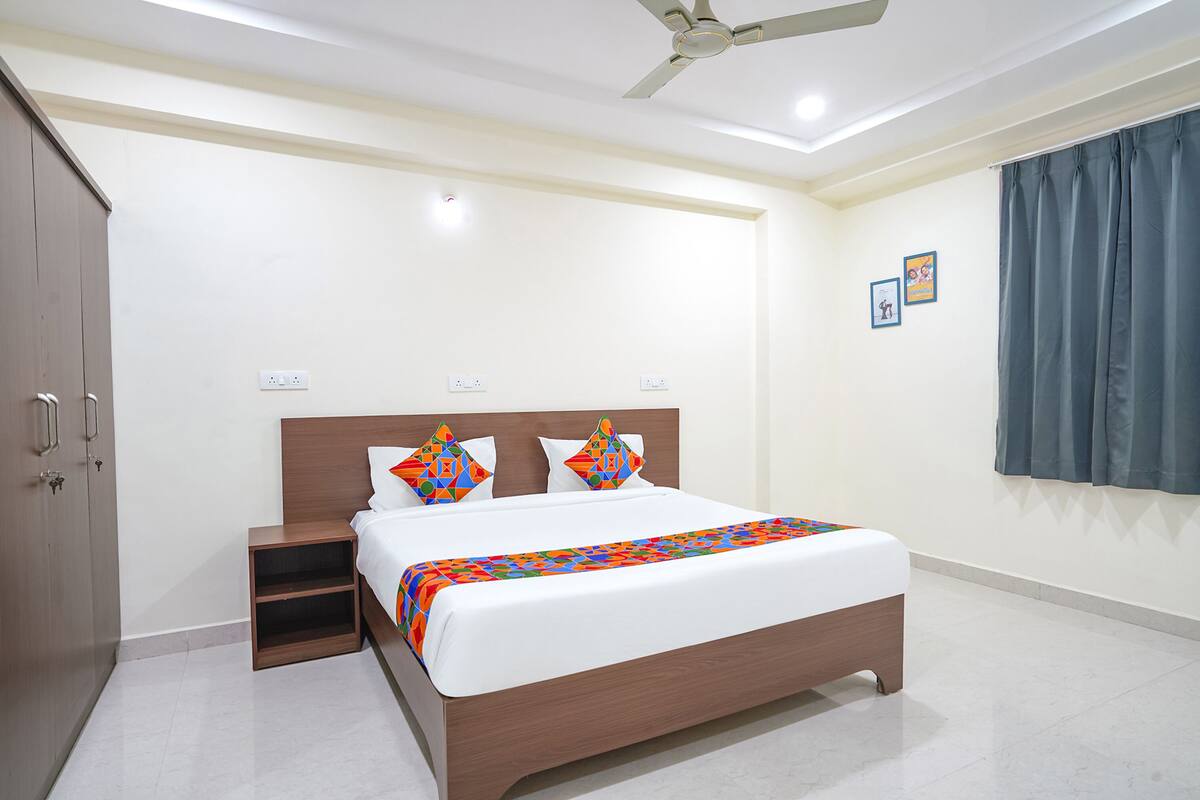 A neatly arranged bedroom with a bed, a nightstand, a wardrobe, and a ceiling fan.