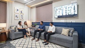 Un salon moderne avec un canapé gris, une table basse et un téléviseur fixé au mur qui diffuse un diaporama.