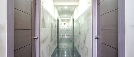 Un pasillo con paredes de mármol y piso reflectante, que conduce a una puerta con una placa de identificación.