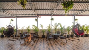 Un patio couvert doté d’un plancher en bois, de chaises en osier et de plantes suspendues.