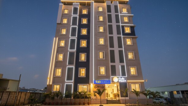 Un hôtel à plusieurs étages, doté d’une façade moderne, de fenêtres illuminées et d’une enseigne « FabHotels ».