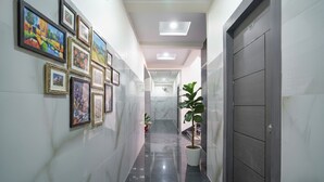 Un couloir orné de tableaux encadrés, avec une plante en pot et une porte moderne.