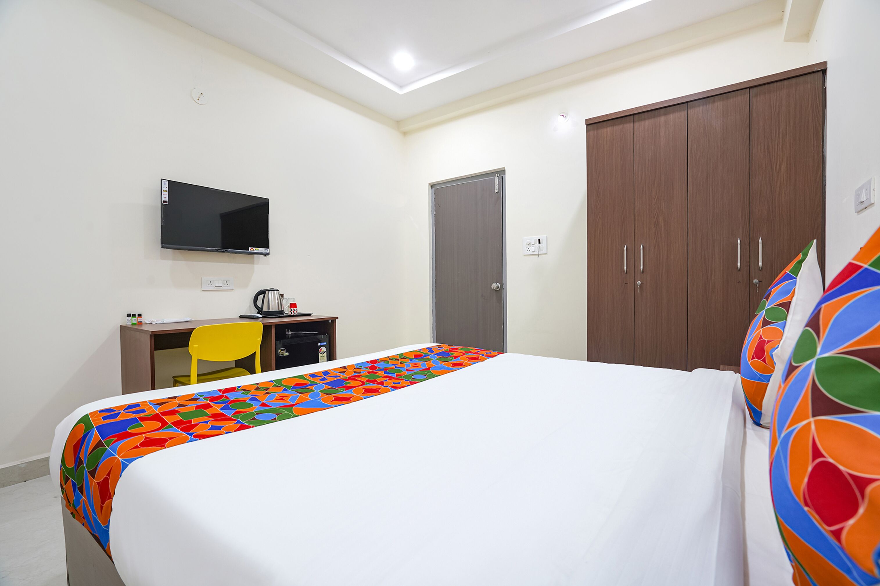 Een hotelkamer met een bed, bureau, stoel, televisie en kledingkast.