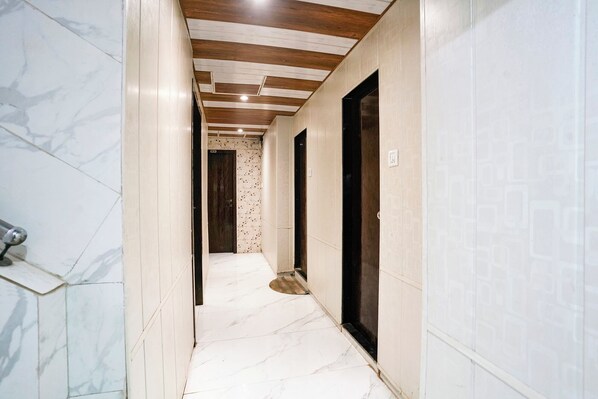 A hallway with white marble flooring, wooden ceiling beams, and a patterned wall.