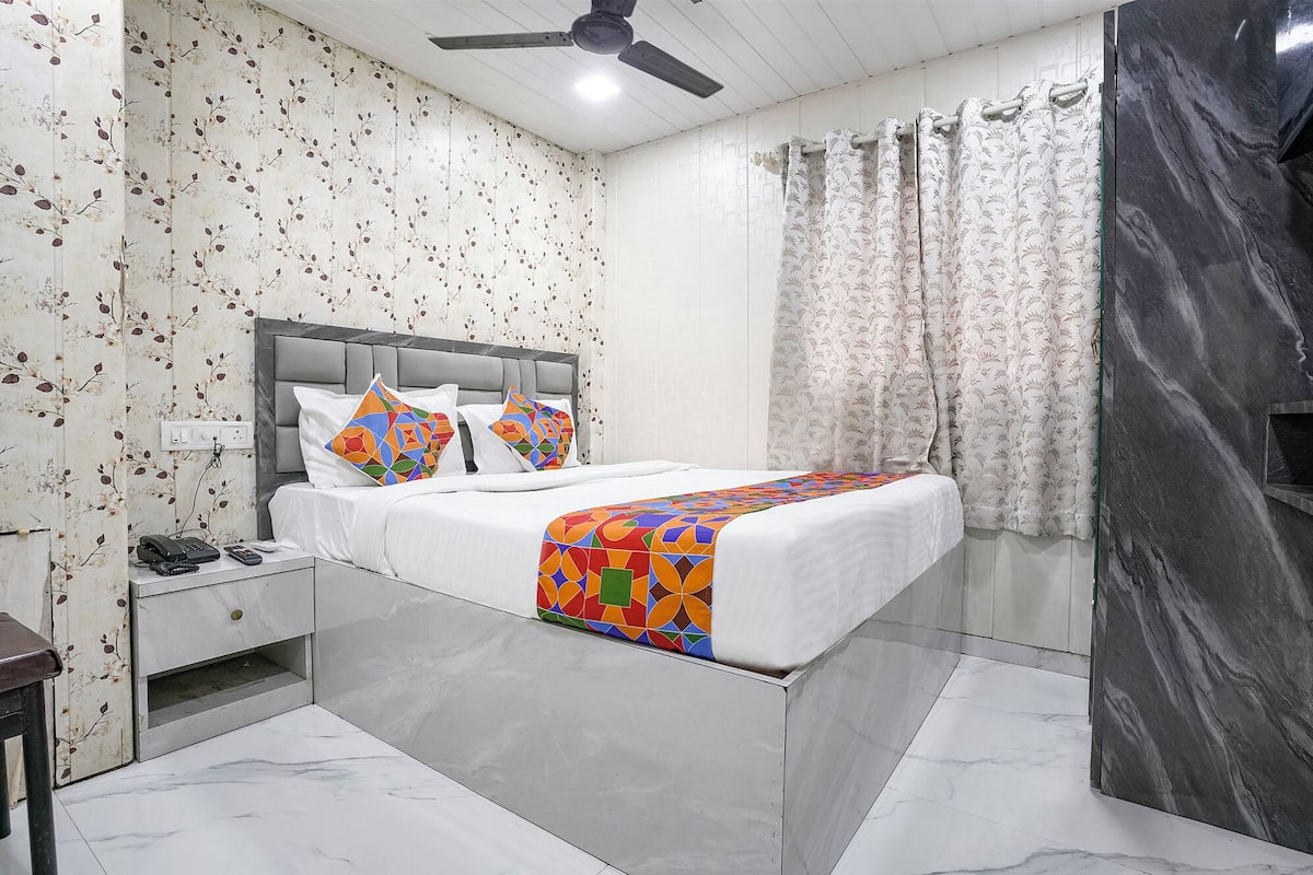 A bedroom with a bed, a nightstand, a telephone, and a ceiling fan.