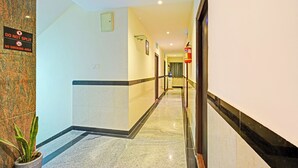 A hotel hallway with a 'No Smoking' sign, a fire extinguisher, and a potted plant. - Fabhotel Aig Broholic (Hyderabad)