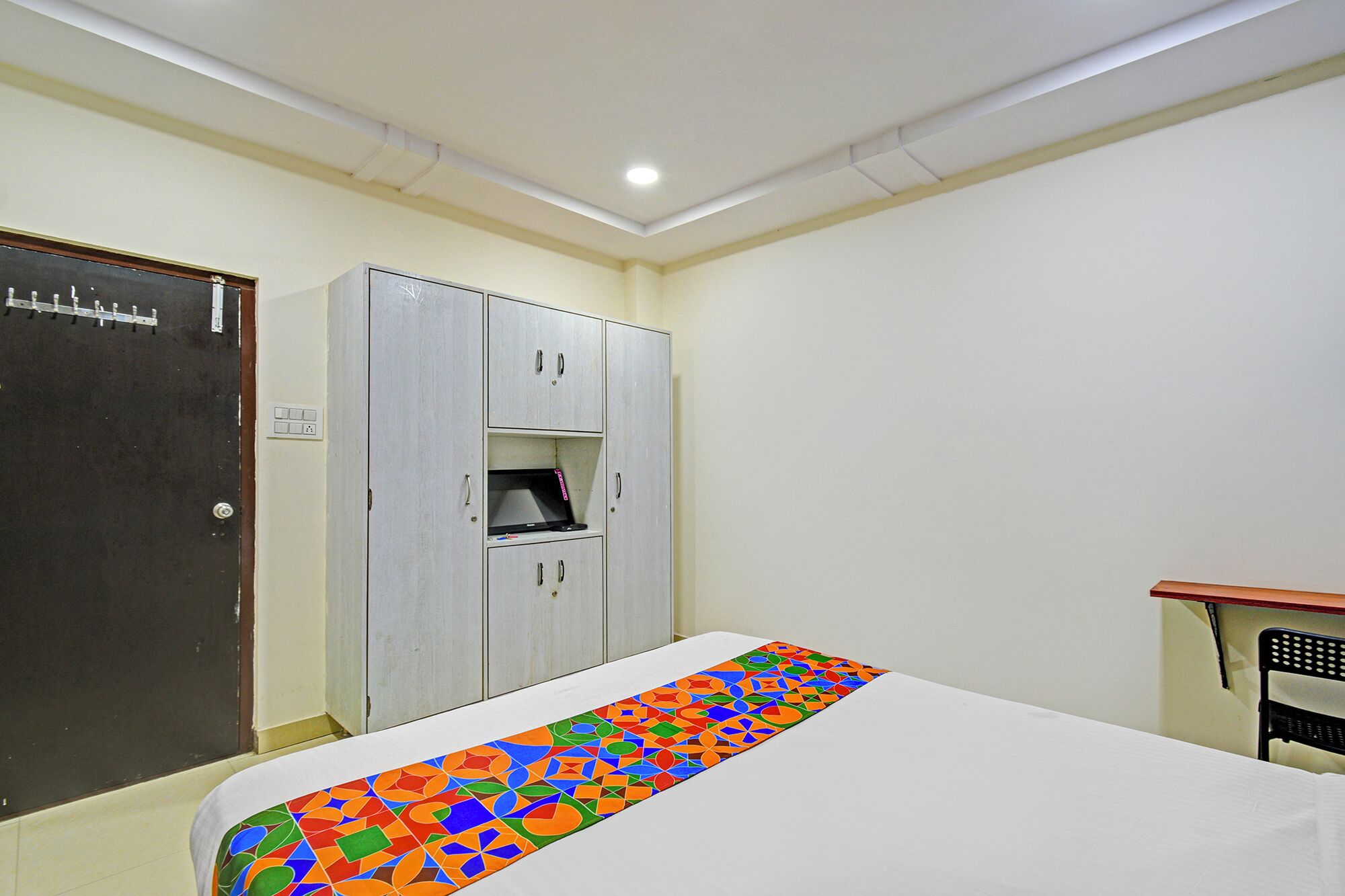 A room with a bed, a wardrobe, a desk, and a door.