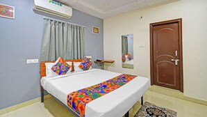 A hotel room with a bed, a ceiling fan, an air conditioner, a door, and a window with curtains. - Fabhotel Aig Broholic (Hyderabad)