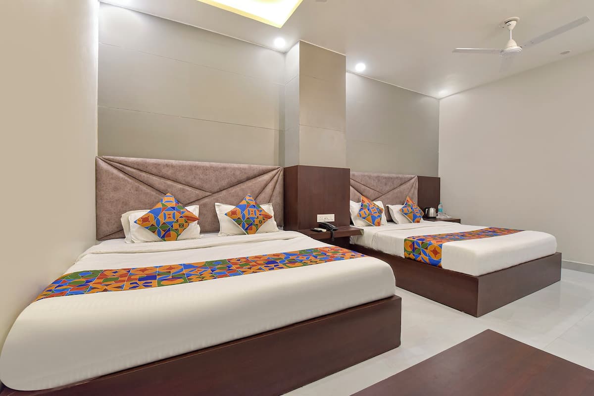 A hotel room with two beds, each with a unique geometric-patterned bedspread.