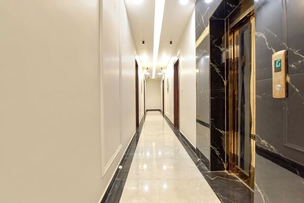 A long, narrow hallway with a marble floor and walls, leading to an elevator. - Fabhotel Mahadev Palace (Haridwar)