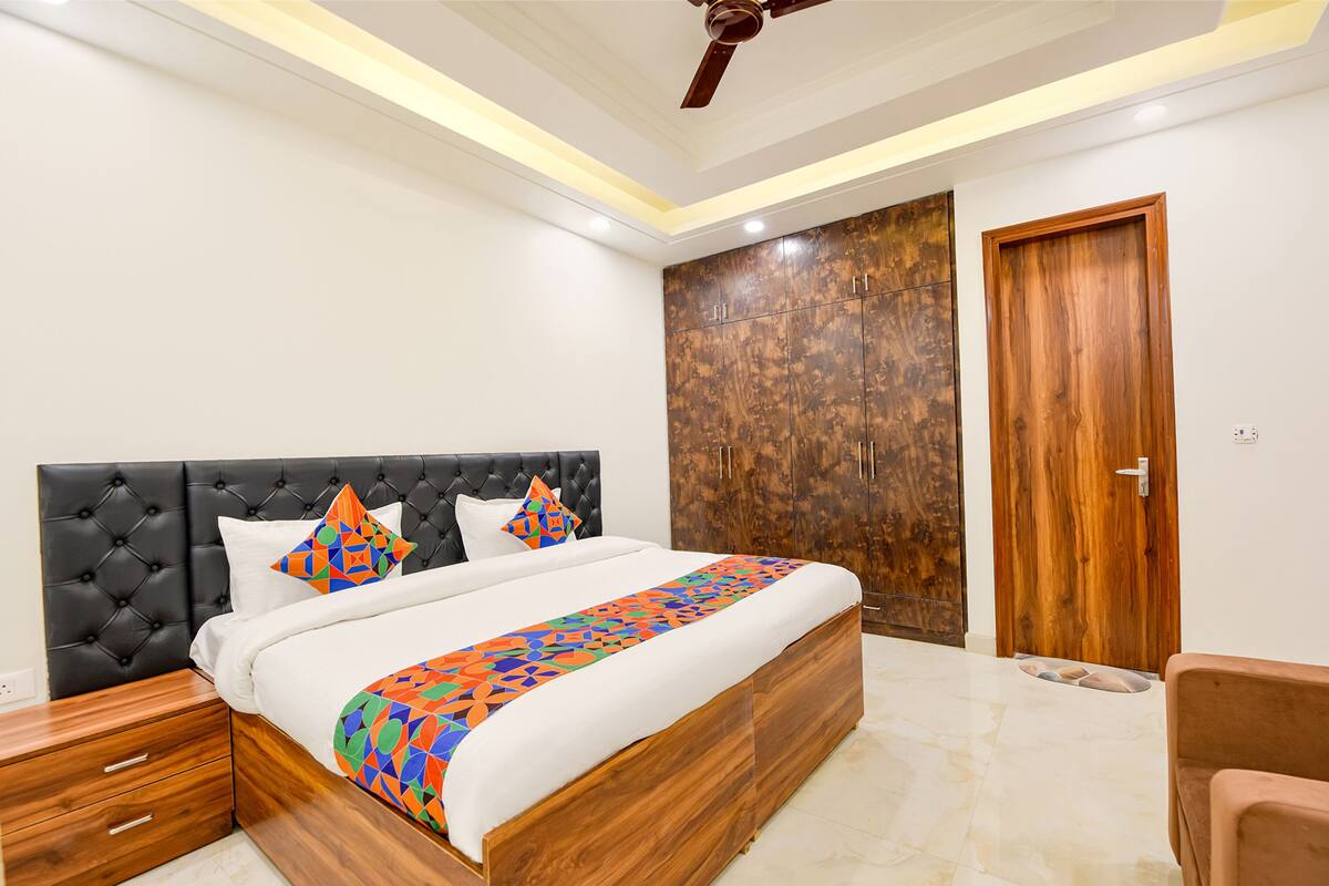 A bedroom with a large bed, a wooden wardrobe, a wooden nightstand, and a ceiling fan.