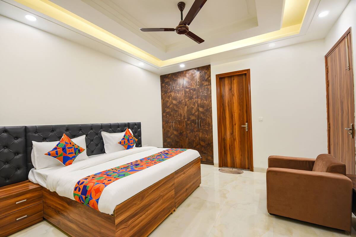 A bedroom with a bed, a ceiling fan, a wardrobe, and a seating area.