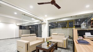 Una sala de estar moderna con una mesa de centro de vidrio, sofás color beige y un ventilador de techo.
